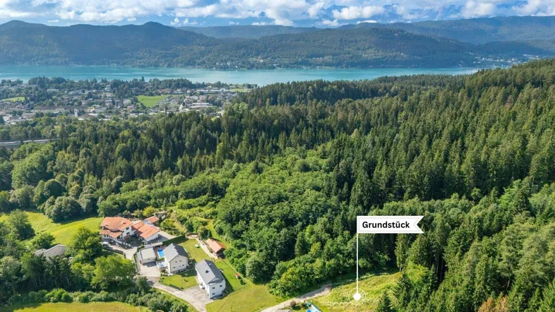 Luftaufnahme der Landschaft mit See, Bergen, Wald und einem markierten Grundstück.
