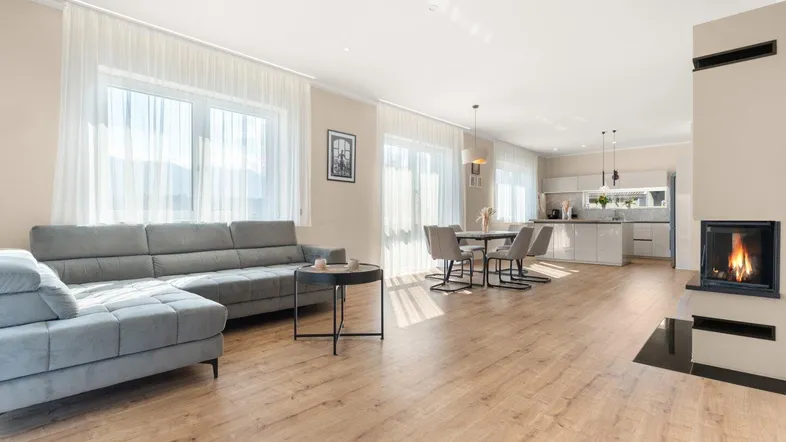 Helles, offenes Wohn-Esszimmer mit integrierter Küche, Kamin und Holzboden.