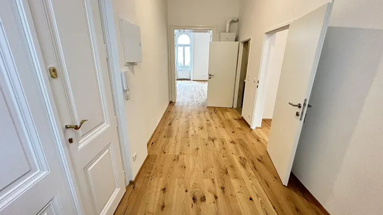 Heller Flur mit neuem Holzparkettboden und weißen Türen, der zu verschiedenen Räumen führt.