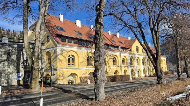 Historisches Gebäude mit markanter gelber Fassade und vielen Fenstern in ländlicher Umgebung.