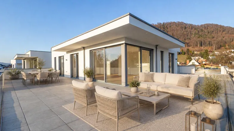 Große, möblierte Dachterrasse mit modernen Loungemöbeln und einem weiten Blick auf die Berge.