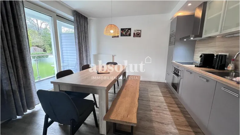 Moderner offener Wohn- und Essbereich mit integrierter Küche und Zugang zum Balkon.