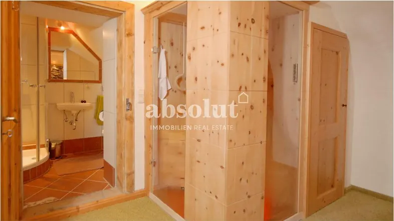 Rustikales Badezimmer mit Holzelementen und einer modernen Duschkabine, passend zum alpinen Stil.
