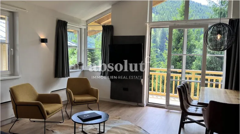 Helles Wohn- und Esszimmer mit großen Fenstern, Holzboden und Bergblick.