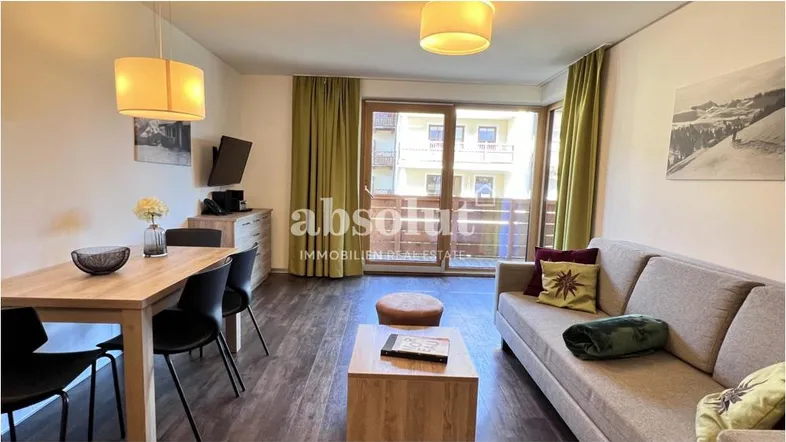 Heller offener Wohn- und Essbereich mit Holzboden, Zugang zum Balkon und Blick auf die Umgebung.