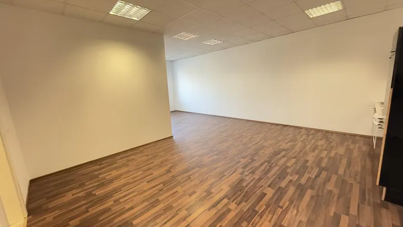 Geräumiger Büroraum mit modernem Laminatboden und abgehängter Decke, bereit zur individuellen Gestaltung.