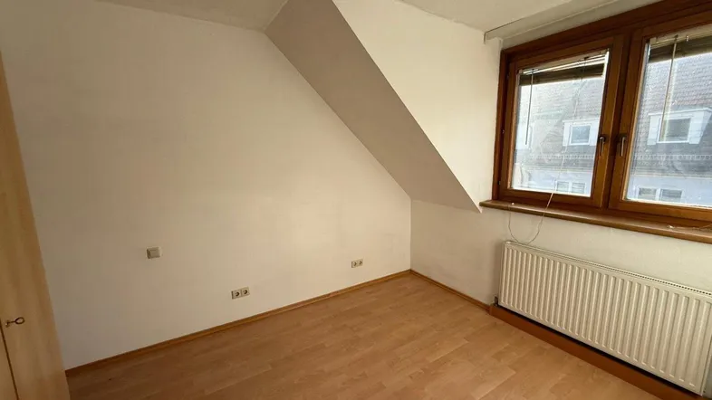 Helles Schlafzimmer im Dachgeschoss mit Laminatboden, Dachschräge und Fenster.