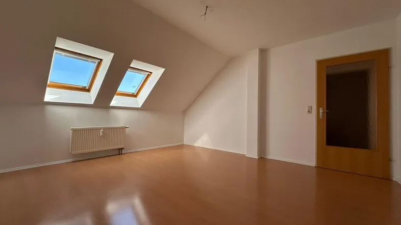 Lichtdurchfluteter Raum im Dachgeschoss mit Laminatboden und zwei Dachfenstern.