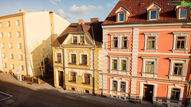 Historische Gebäude mit farbigen Fassaden und Satteldächern an einer Straße.