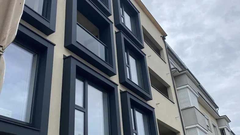 Moderne Gebäudefassade mit markanten schwarzen Fensterrahmen und Balkonen, die einen urbanen Eindruck vermitteln.