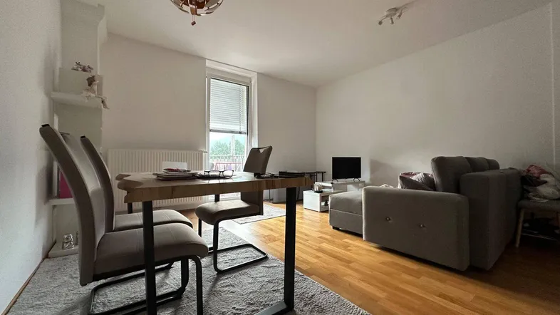 Heller Wohn- und Essbereich mit Holzboden, Esstisch und gemütlichem Sofa.