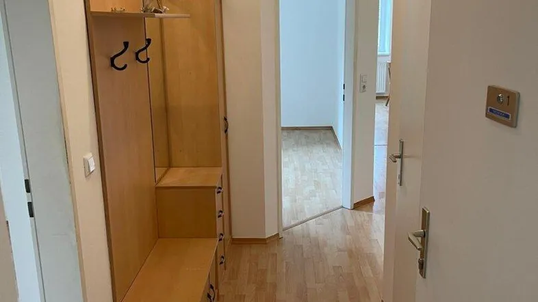Heller Flur mit Laminatboden und praktischer Garderobe, der zu weiteren Räumen führt.