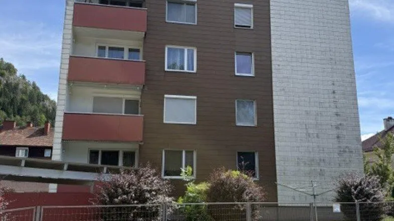 Mehrstöckiges Wohngebäude mit Balkonen und einer Mischfassade unter blauem Himmel.