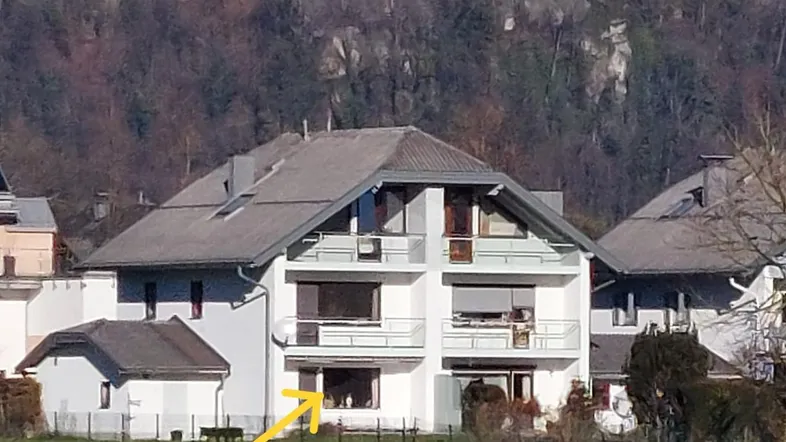 Weißes Wohnhaus mit Balkonen und Blick auf die Festung Hohensalzburg im Hintergrund.