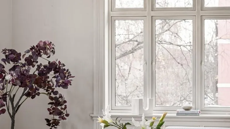 Helles Wohnzimmer mit hohen Decken, großem Fenster und moderner Einrichtung, inklusive stilvoller Beleuchtung.