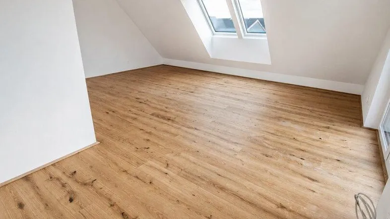 Geräumiges Dachgeschosszimmer mit hellem Holzboden und einem großen Dachfenster für viel Tageslicht.