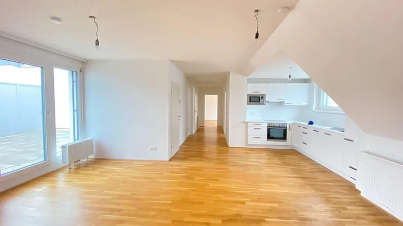 Helles, offenes Wohn-Esszimmer mit integrierter Küche, Parkettboden und Zugang zur Terrasse.