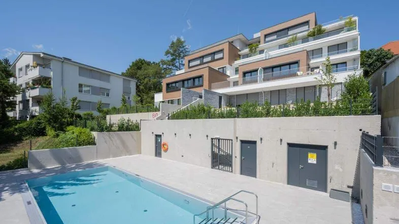 Moderne Wohnanlage mit Außenpool und Terrassen in sonniger Hanglage.