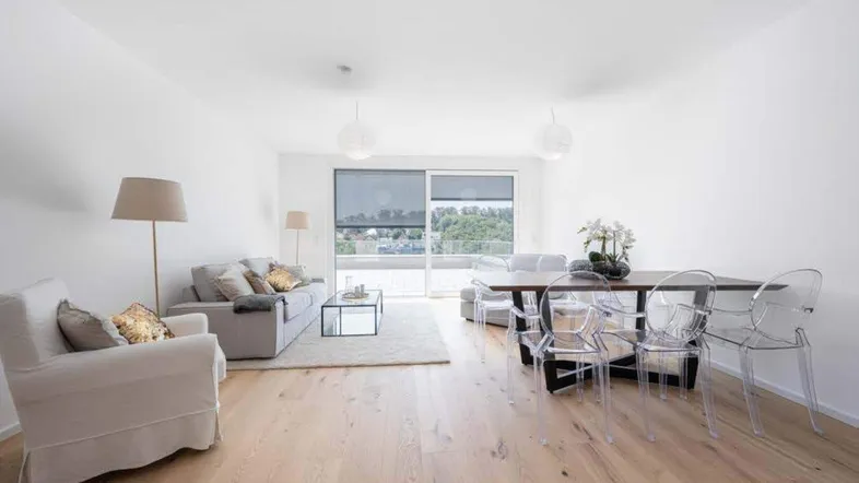 Helles, offenes Wohn- und Esszimmer mit Holzboden und Zugang zu einem Balkon.