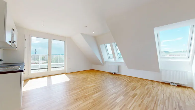 Heller Wohnbereich im Dachgeschoss mit Holzboden, Dachfenstern und Zugang zum Balkon.