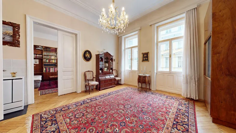 Elegantes Wohnzimmer mit Fischgrätparkett, Kronleuchter und hohen Decken im Altbau.