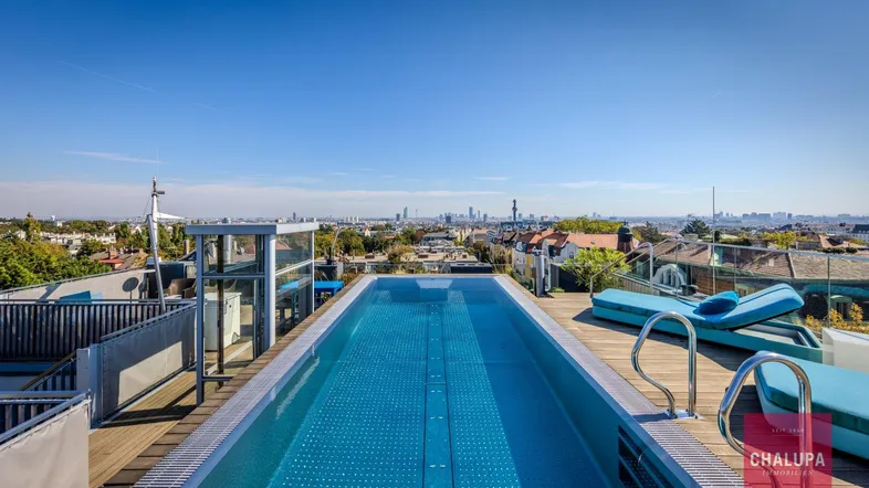 Exklusiver Dachterrassenpool mit Holzdeck, bequemen Liegen und weitem Stadtblick unter blauem Himmel.