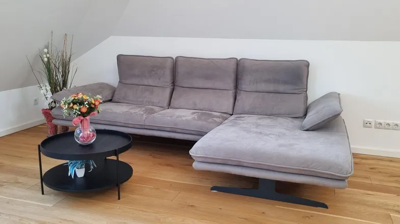 Gemütliches Wohnzimmer im Dachgeschoss mit bequemer Couch und Holzboden.