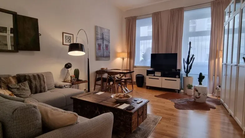 Gemütlicher Wohn- und Essbereich mit Sofa, Esstisch und Blick auf die Straße.