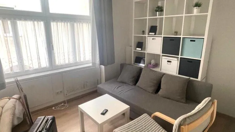 Helles Wohnzimmer mit Sofa, Couchtisch und großem Fenster, das viel Tageslicht hereinlässt.