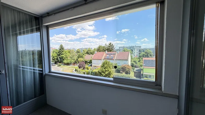 Verglaste Loggia mit weitem Blick über die umliegenden Wohnhäuser und viel Grün.