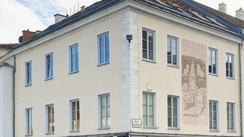 Historisches Eckgebäude mit mehreren Etagen und Geschäftsflächen im Erdgeschoss an einer belebten Straße.