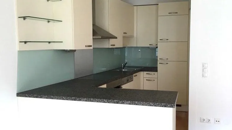 Moderne Küche mit beigen Schränken, dunkler Granitarbeitsplatte und integrierter Frühstückstheke.