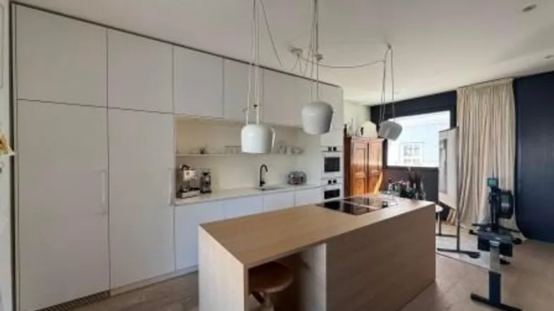 Moderne Küche mit weißen Schränken, Holzinsel und integrierten Geräten, offen gestaltet.