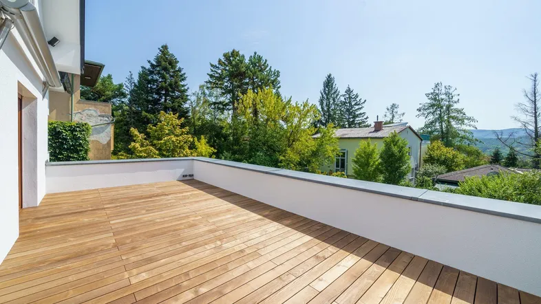 Große Holzterrasse mit weitem Blick ins Grüne und auf die umliegende Landschaft.