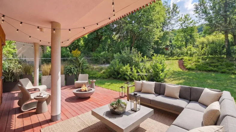 Geräumige Terrasse mit gemütlicher Sitzecke, Feuerstelle und Blick ins Grüne, ideal für entspannte Abende.