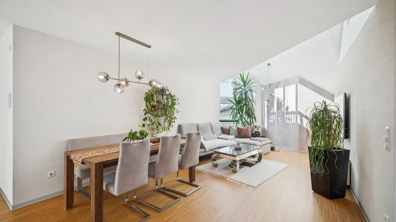 Heller Wohn- und Essbereich mit Holzboden, modernem Esstisch und gemütlichem Sofa.