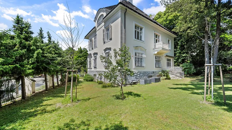 Elegante Villa mit gepflegtem Garten und klassischer Architektur unter blauem Himmel.