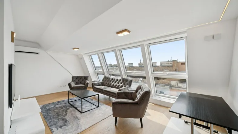Helles Wohnzimmer mit Dachschrägen, großen Fenstern und moderner Einrichtung.