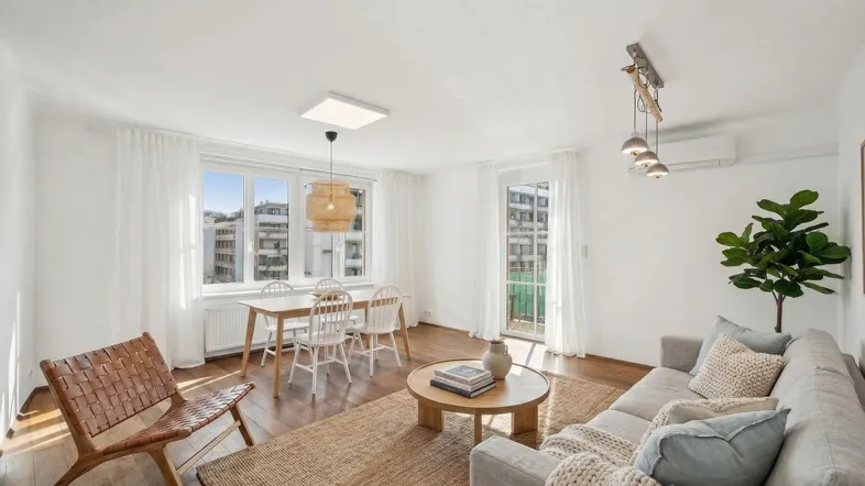 Helles Wohn- und Esszimmer mit Holzboden, modernen Möbeln und Zugang zum Balkon.