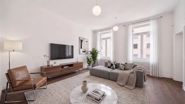 Helles Wohnzimmer mit modernem Sofa, Holzboden und großen Fenstern, die viel Tageslicht hereinlassen.