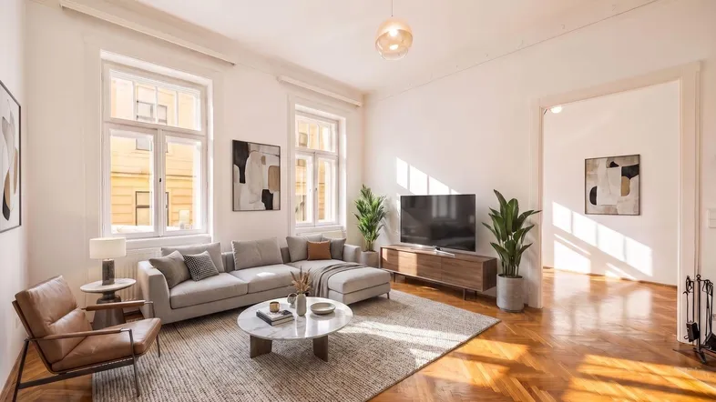 Helles Wohnzimmer mit Fischgrätparkett, modernem Sofa und großen Fenstern, die viel Tageslicht hereinlassen.