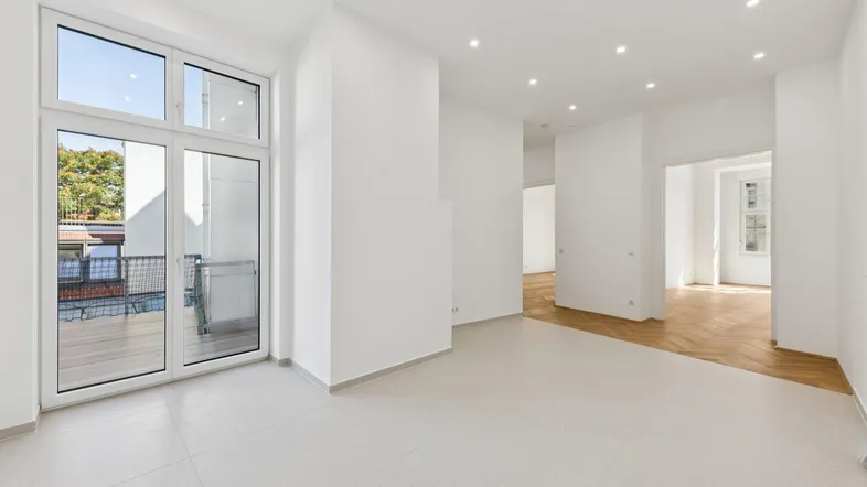 Helles, frisch renoviertes Wohnzimmer mit Fliesenboden, Einbaustrahlern und Zugang zu einem Balkon.