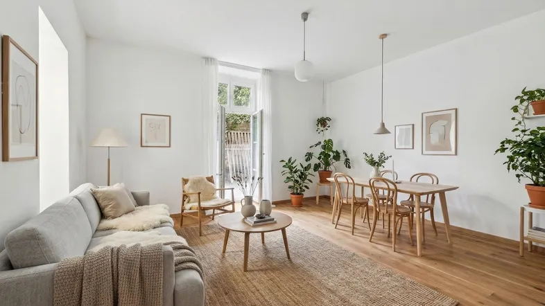 Helles Wohn- und Esszimmer mit Holzboden, modernen Möbeln und vielen Pflanzen.