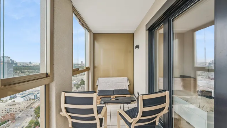 Moderner Balkon mit Sitzgelegenheiten und weitem Blick über die Stadt.