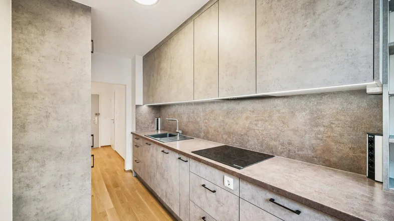 Moderne Küche mit grauen Schränken, Holzfußboden und integriertem Induktionskochfeld.