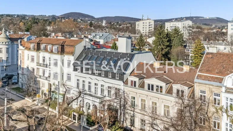 Panoramablick über die Dächer der Stadt mit grünen Hügeln im Hintergrund und historischer Architektur.