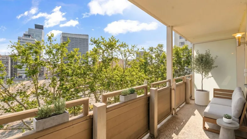 Geräumiger Balkon mit Sitzgelegenheiten, Pflanzen und einem weiten Blick auf die Stadt.