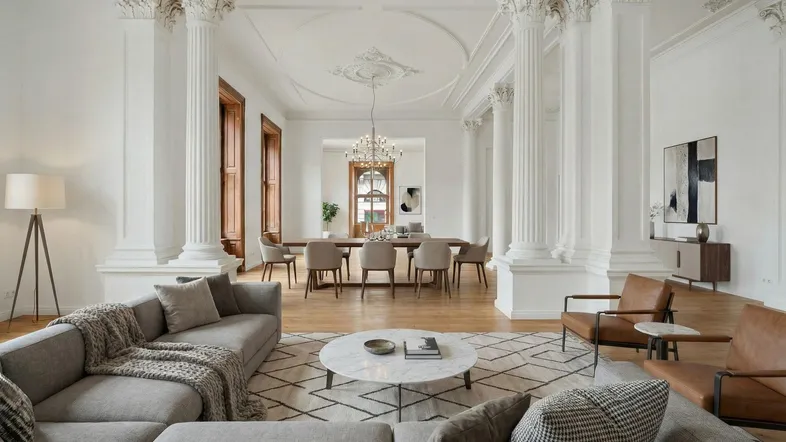 Elegantes Wohn- und Esszimmer mit hohen Decken, Stuckverzierungen und klassischen Säulen.