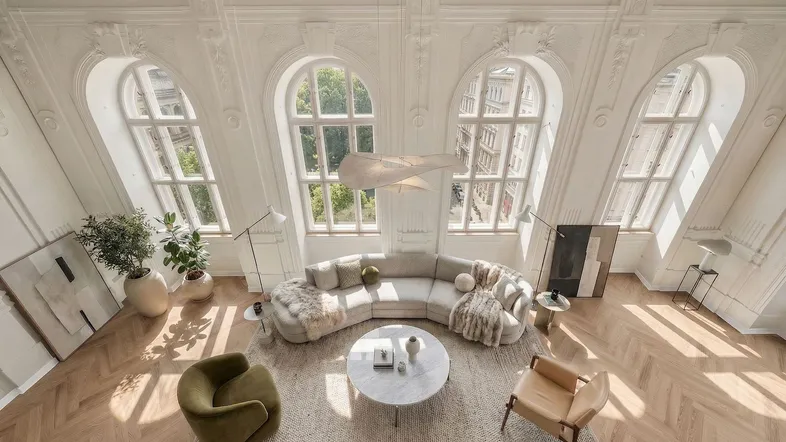 Helles, luxuriöses Wohnzimmer mit hohen Decken, Stuckverzierungen und großen Bogenfenstern, die viel Licht hereinlassen.