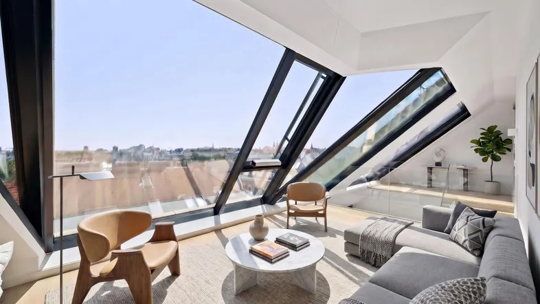 Helles, modernes Wohnzimmer mit großen, schrägen Fenstern und Panoramablick über die Stadt.